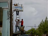 Allt löst plockas ner inför orkanen. Här: en skylt som sticker ut från en fasad. 