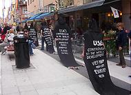 Protesterande människor i svarta huvor med USA-kritiska texter, ex.vis: USA:s contribution to the world development: aggressions against Panama  5 000 victims